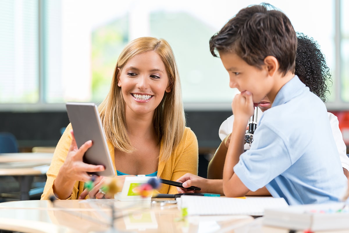 STEM school teacher uses digital tablet to help student